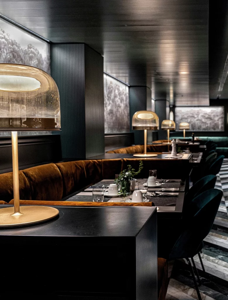 Sala ristorante Hilton Rome EUR La Lama con lampade dorate, sedute in velluto verde tavoli neri in atmosfera soffusa