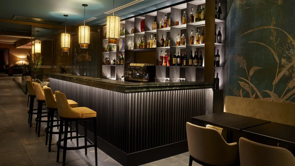 Area bar con bancone e parete attrezzata in legno pregiato dell'hotel Uvisionary Venezia