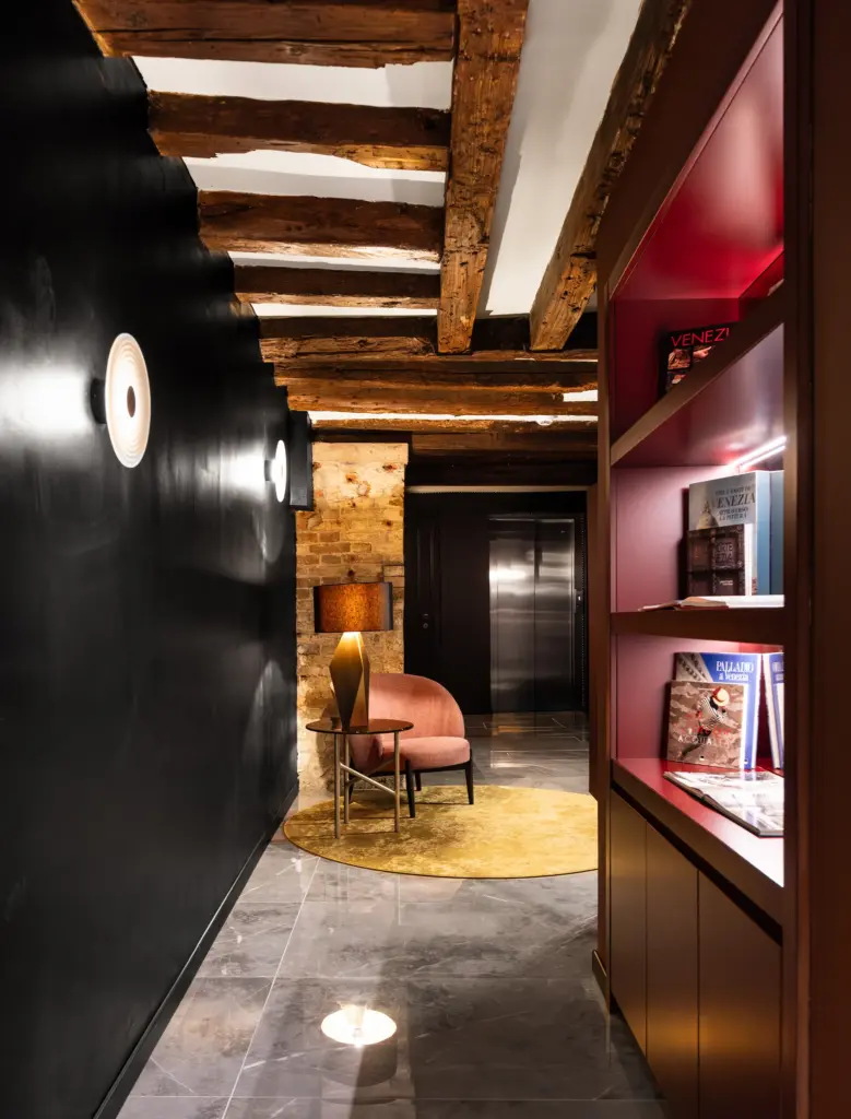 Corridoio di Palazzo Rota con travi a vista, pareti nere e libreria illuminata, progetto hotellerie firmato Antonacci Falegnamerie