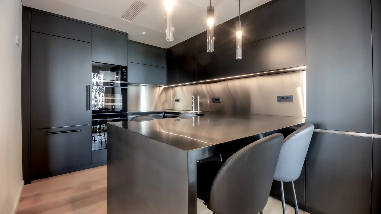 Cucina con isola in acciaio inox e arredi su misura in legno nero, design residenziale Antonacci Falegnamerie.